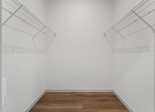 an empty room with white walls and wooden floors and wire shelves on the wall