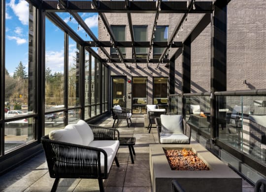 a patio with chairs and a coffee table and large windows