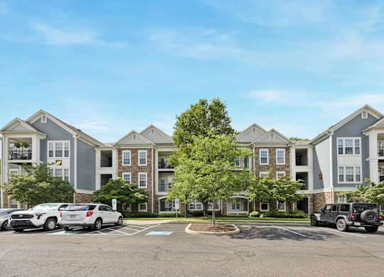 A large apartment complex with a parking lot in front.