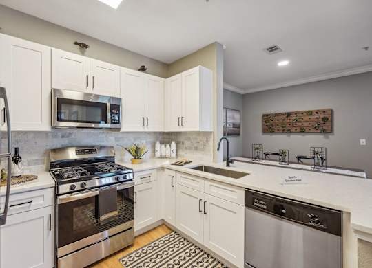 A modern kitchen with white cabinets and stainless steel appliances.