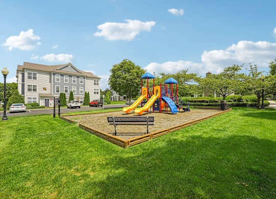 A playground with a slide and a wooden platform in the middle of a grassy area.