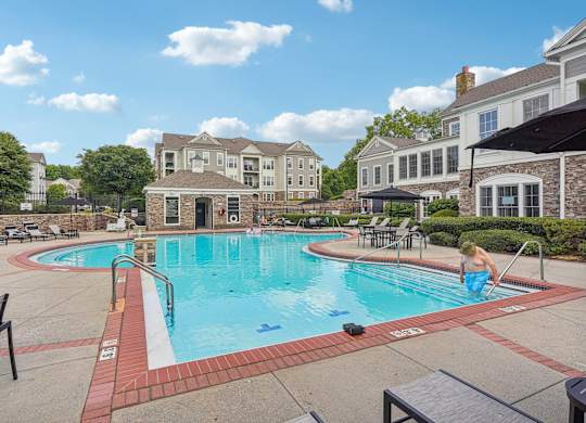 A man is sitting on the edge of a swimming pool.