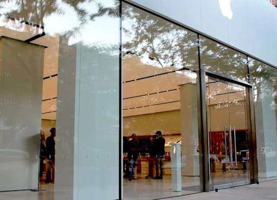 A glass facade of a building with the Apple logo on it.
