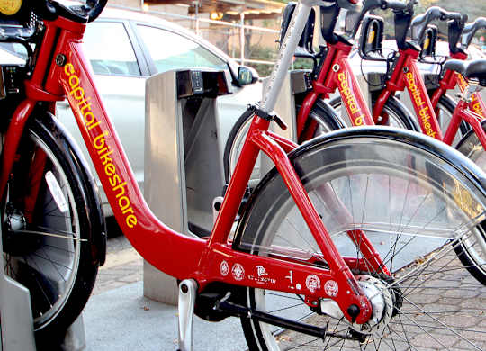 A row of red bikes are parked next to each other.