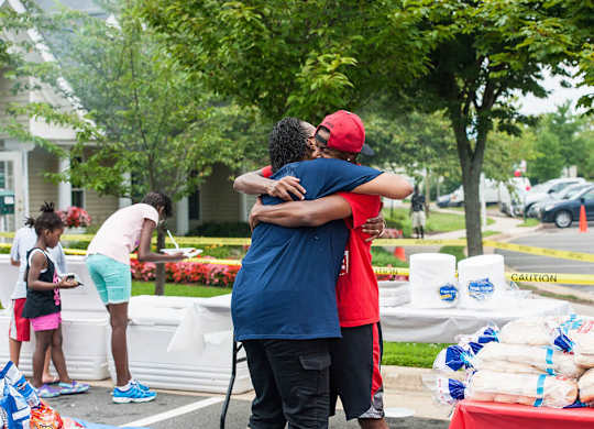 Two people hug each other in front of a table with bags of food.