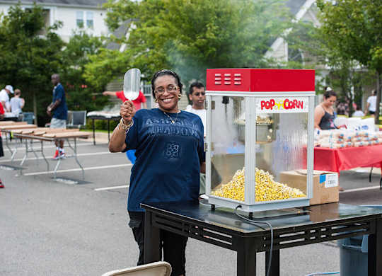 A woman is standing in front of a popcorn machine.