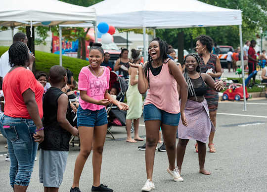 A group of people are standing under a white tent.