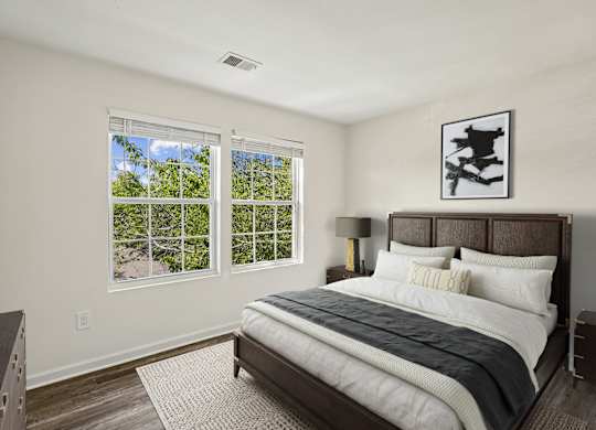A bedroom with a large bed and a window overlooking a tree-filled landscape.