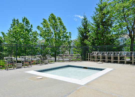 A small pool surrounded by a fence and trees.