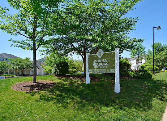 A sign for Ashdown Apartments stands in a grassy area.