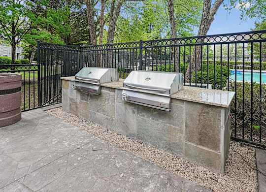 A black metal fence surrounds a stone wall with two mailboxes on it.