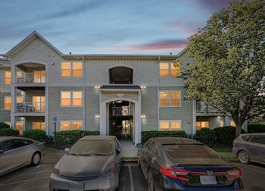 Three cars are parked in front of a building with a garage.