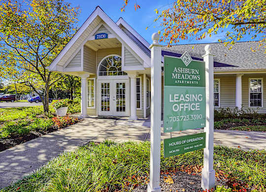 A sign for Ashburn Meadows Apartments leasing office stands in front of a building.
