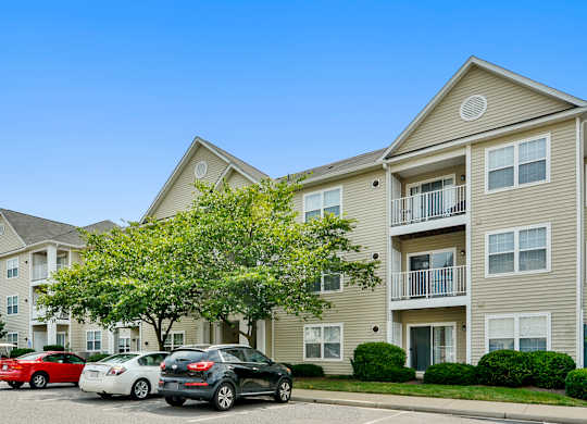 A black car is parked in front of a two-story apartment building.