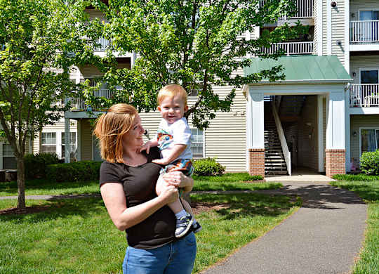 A woman holding a baby in front of a building.
