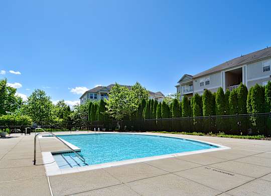 A swimming pool surrounded by a fence and trees.