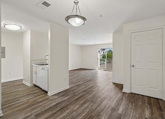 A large empty room with wood flooring and a ceiling light.