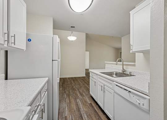A kitchen with white cabinets and a white sink.