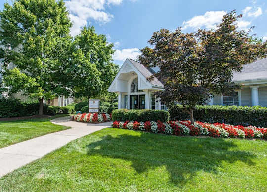 A white house with a green lawn and a sign in front.