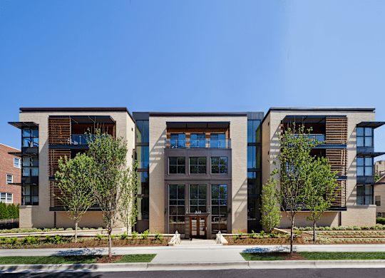 A modern building with a glass entrance and two trees in front.