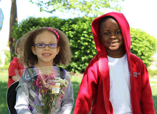 A young girl with glasses is holding a bouquet of flowers.