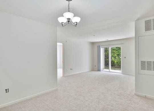 A spacious, empty room with a chandelier and a window.