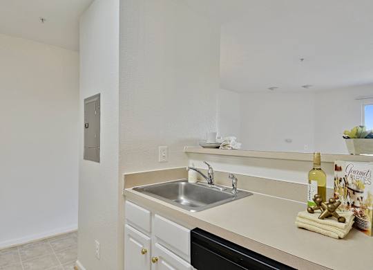 A kitchen with a sink and a counter with a bottle of wine on it.