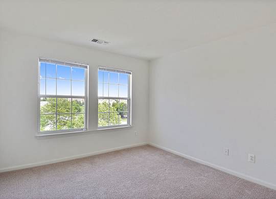 A room with two windows and carpeted floor.