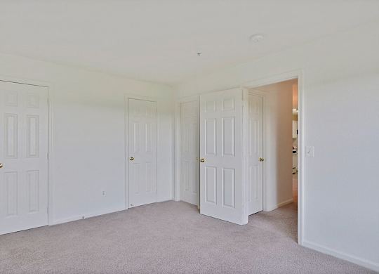 A room with white doors and carpeted floor.