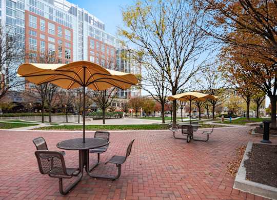 A yellow umbrella is over a round table with four chairs.