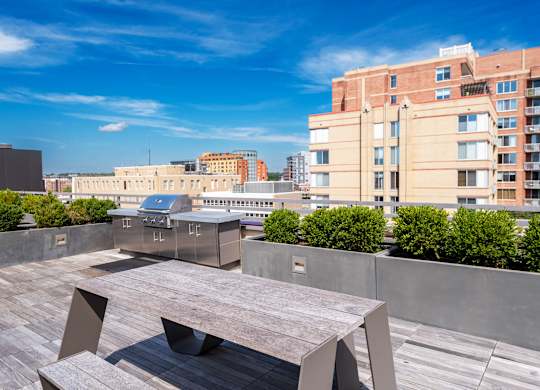 A modern outdoor seating area with a large table and chairs overlooking a cityscape.
