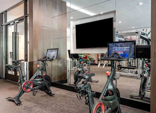 A gym with stationary bikes and a TV screen.