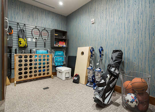 A room with a wooden floor and a blue wall with a basket of balls and a pair of shoes.