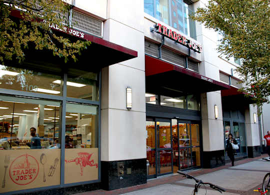 A Trader Joe's storefront with people walking by and bicycles parked outside.