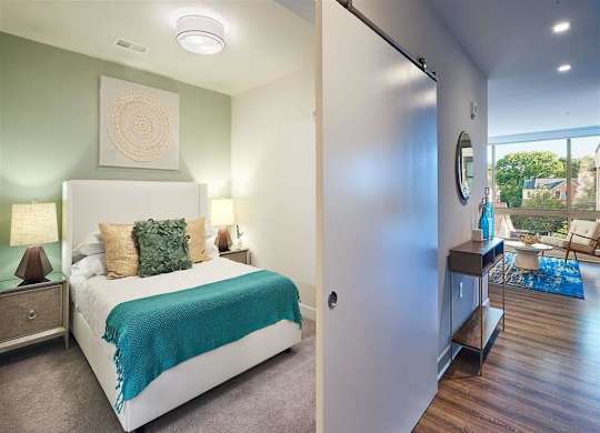 A bedroom with a bed, nightstand, and a mirror on the wall.