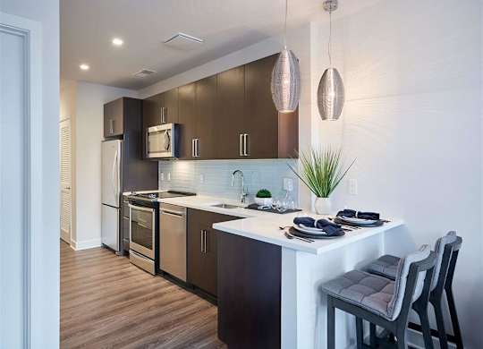 A modern kitchen with dark brown cabinets and a white countertop.