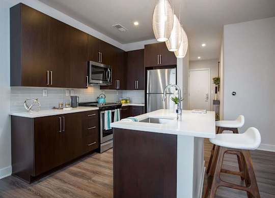 A modern kitchen with dark brown cabinets and a white countertop.