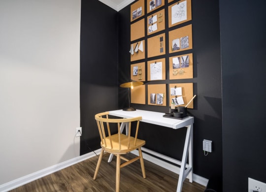 a small desk with a wooden chair in front of a black wall