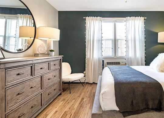 Large bedroom featuring queen size bed, full size dresser, and accent chair at Alister Morristown, Morristown, NJ, 07960