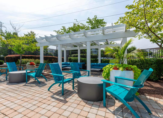 a patio with blue chairs and tables and a white pergola
