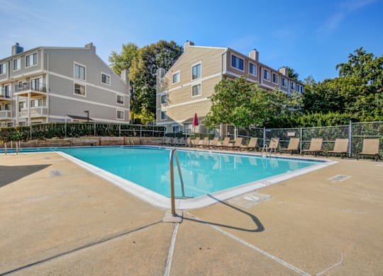A swimming pool in front of a building with a fence around it.