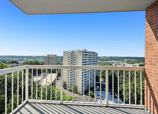 A balcony overlooks a cityscape with buildings and a river.