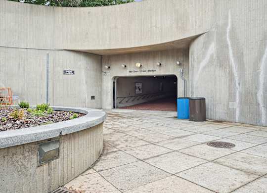 A concrete tunnel entrance with a blue trash can in front.