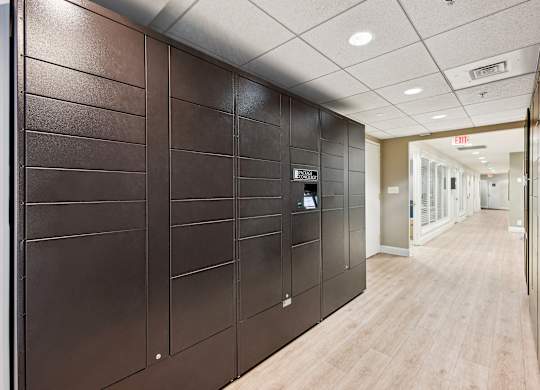 A long hallway with wood floors and a brown wall with a door at the end.