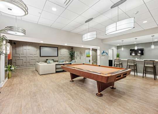 A billiard table is in the middle of a room with a television and a couch.