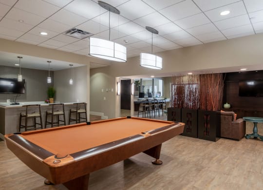 a pool table in a clubhouse with a bar and a tv