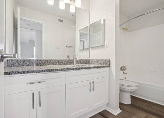 A bathroom with a toilet, sink, and mirror.