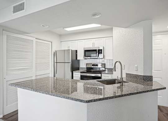 A kitchen with granite countertops and white cabinets.