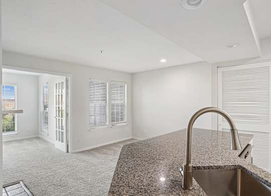 A kitchen with a granite countertop and a stainless steel sink.