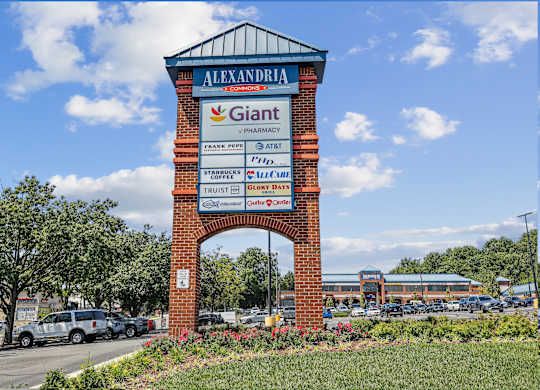 A brick sign for Giant Pharmacy is in front of a parking lot.